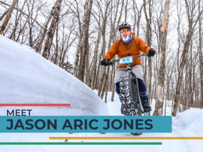 Jason Aric Jones riding mountain bike through woods in snow