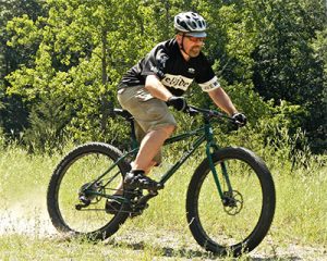 Jason Aric Jones riding mountain bike on dirt path