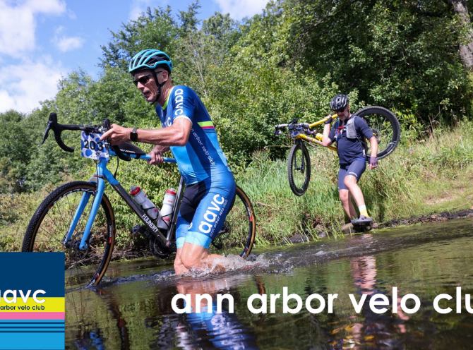 Two cyclists carrying their bicycles through a stream crossing during an off-road cycling race in Michigan
